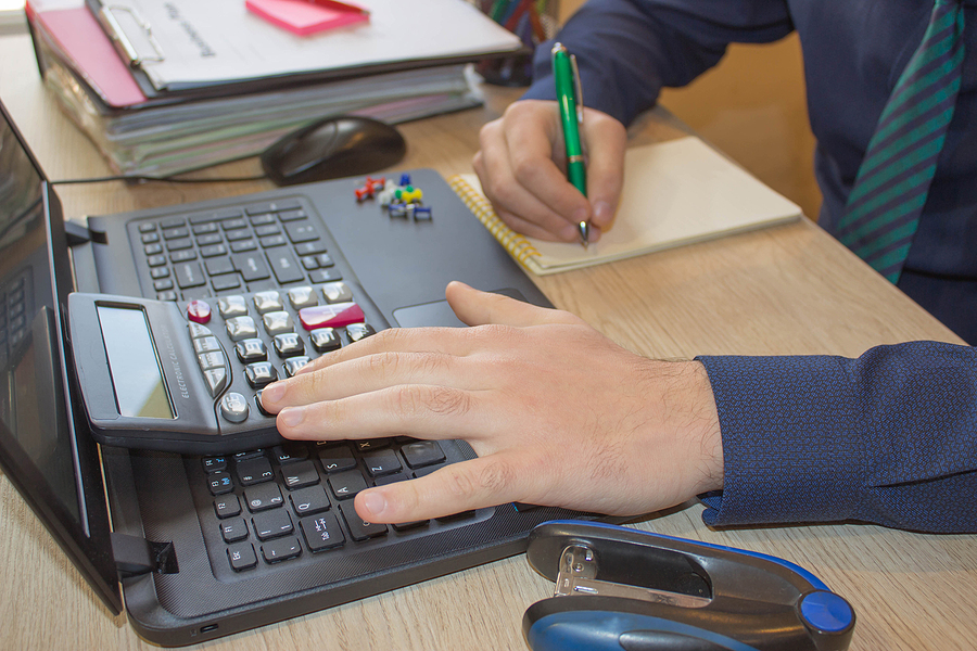 Hands of accountant with calculator and pen. Accounting background. Businessman using a calculator to calculate the numbers. Man hand with calculator at workplace office
